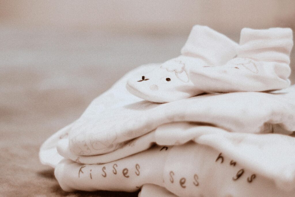 10 Essential Amazon Baby Registry Finds for a Stress-Free First Year Close-up of soft white baby clothes with cute animal patterns, ideal for newborn comfort.